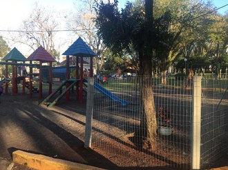Fotografia, em plano aberto, do parque localização na praça de Cerro Largo. É um parque com brinquedos para crianças.