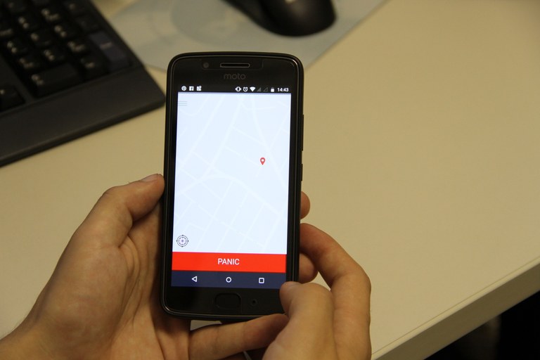 Em um smartphone, aplicativo é mostrado. Na tela, um mapa com a localização, além do botão "Pânico" são mostrados