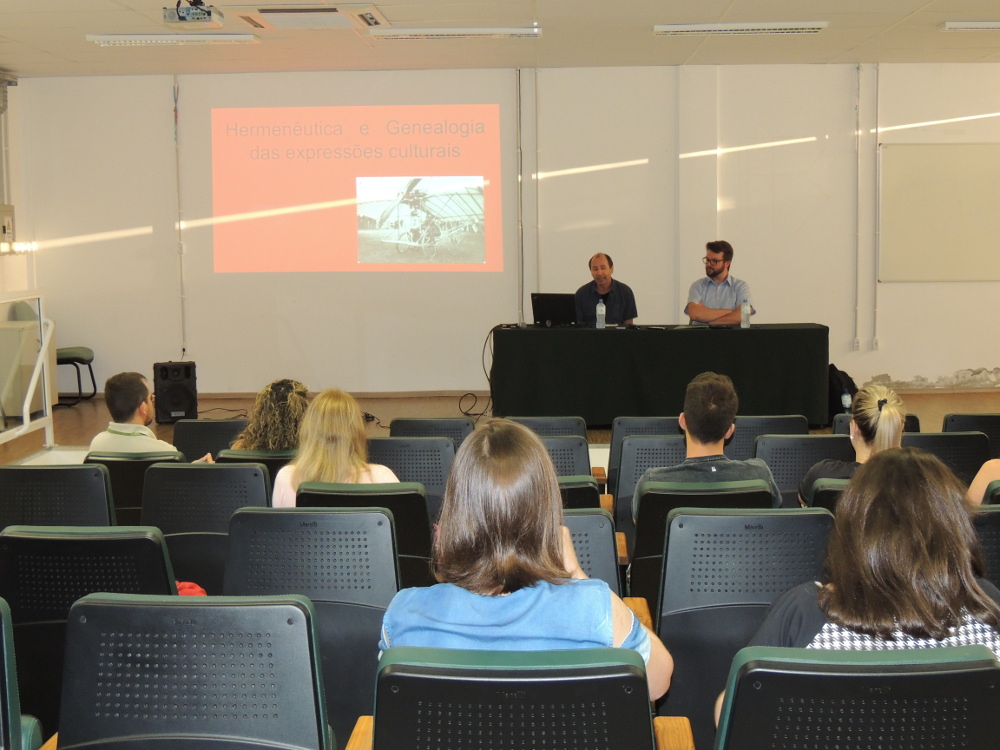 Foto da palestra com Celso Braida, com o professor sentado em uma mesa e com plateia na frente